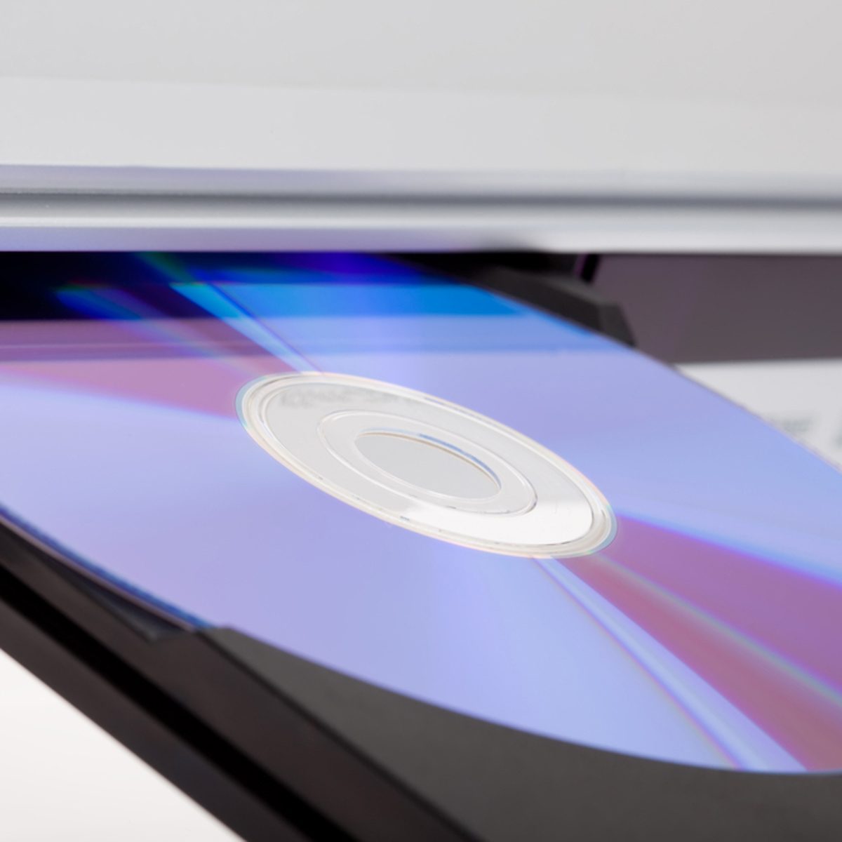 A CD is positioned in a tray, reflecting light in various colors, as it prepares for data reading in an electronic device.