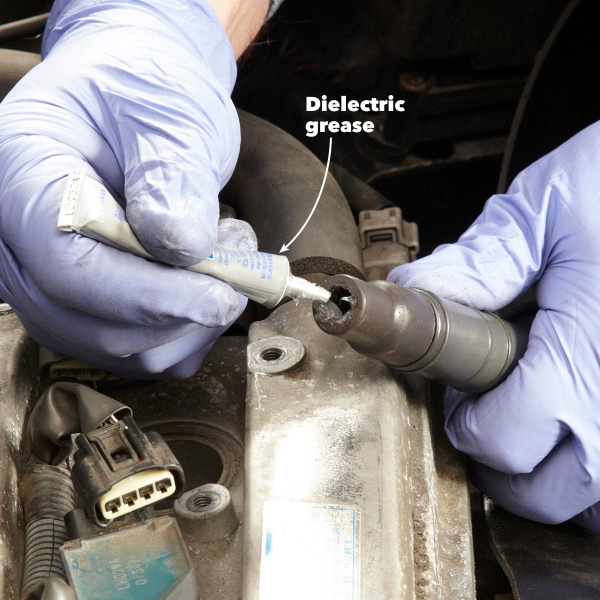 A gloved hand applies dielectric grease to a connector on an engine, ensuring effective electrical insulation in a mechanical maintenance context.