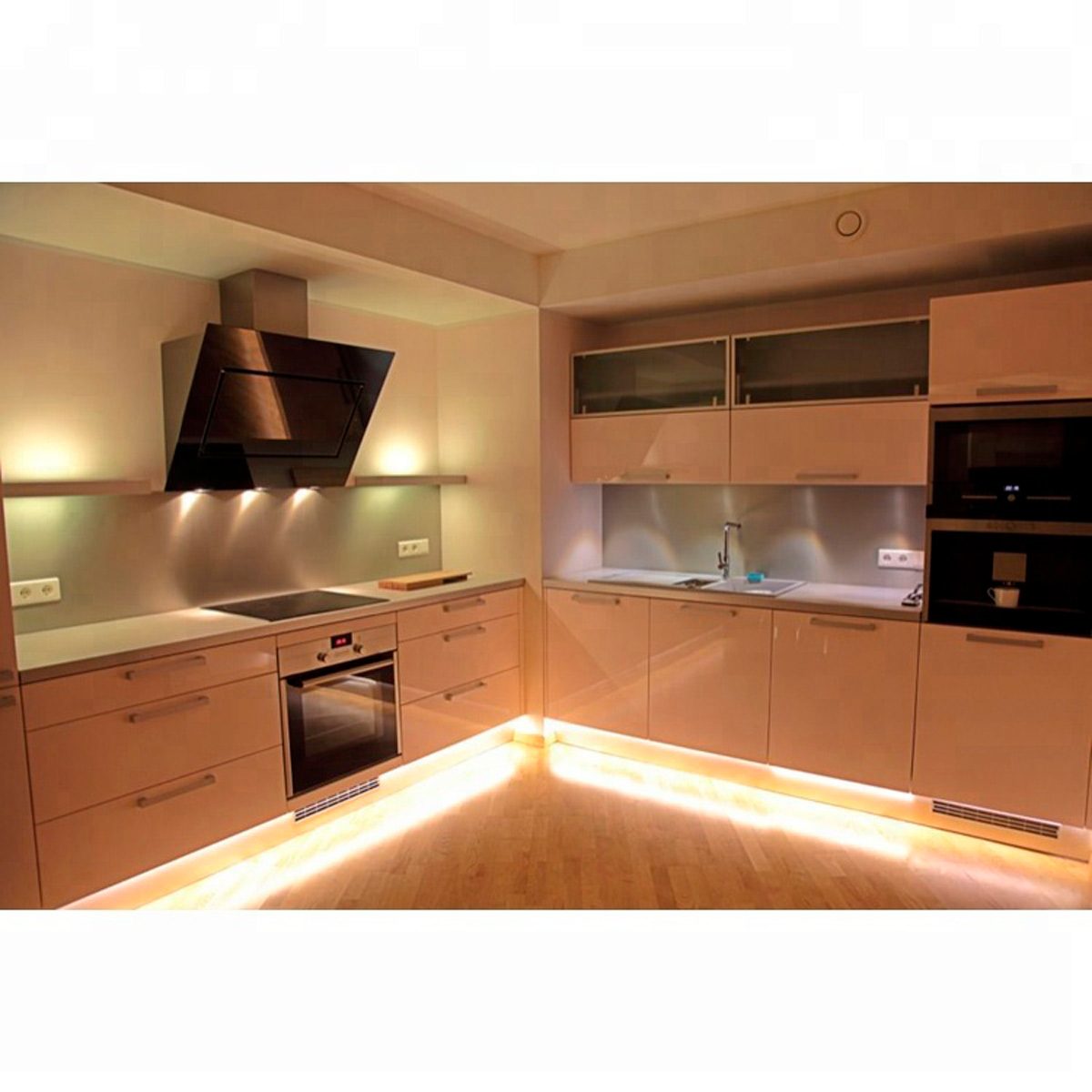 A modern kitchen features sleek cabinets, an induction cooktop, and a wall oven, illuminated by soft lighting, creating a stylish, functional cooking space.