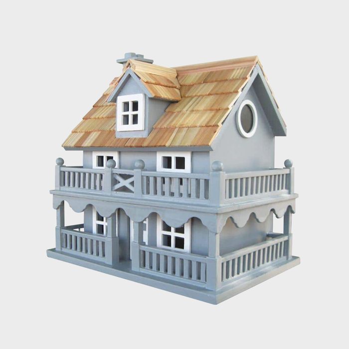 A toy house with a gray body, wooden shingle roof, and two balconies displays intricate details, set against a plain white background.