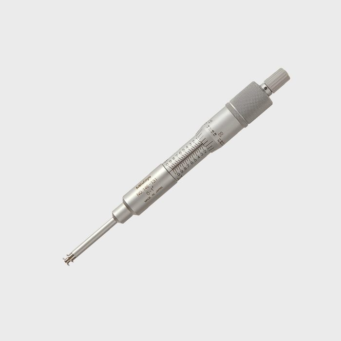 A silver micrometer measures small dimensions, with a calibrated scale on its body, designed for precision in a technical or mechanical environment.