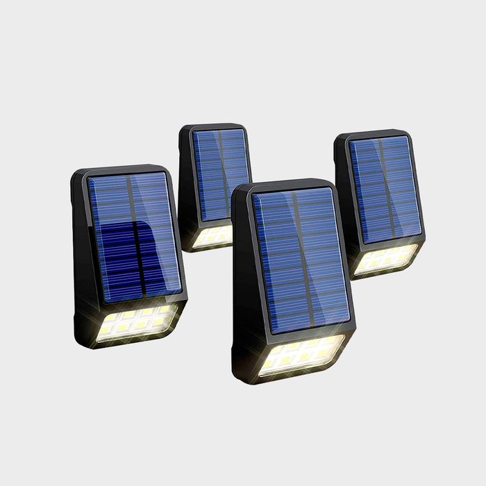 Four solar-powered lights are arranged upright, with blue solar panels on top and bright white LED lights at the bottom, set against a plain background.