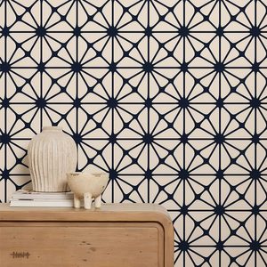 A wooden dresser supports two decorative vessels against a patterned wall of blue and cream geometric shapes, creating a stylish interior ambiance.