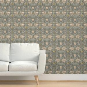 A light-colored sofa rests on wooden flooring, facing a patterned wallpaper featuring floral designs in muted colors, creating a cozy, traditional setting.