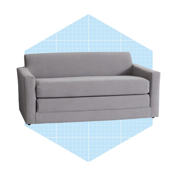 A gray sofa rests against a light blue grid-patterned background, showcasing its simple, modern design with clean lines and a comfortable appearance.