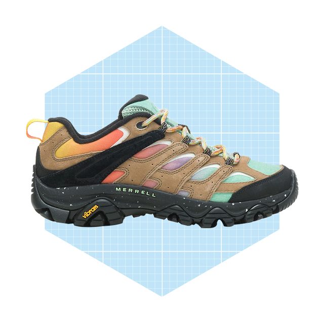 A hiking shoe is displayed on a light blue grid background, showcasing a colorful design with mixed materials and a rugged sole for outdoor use.