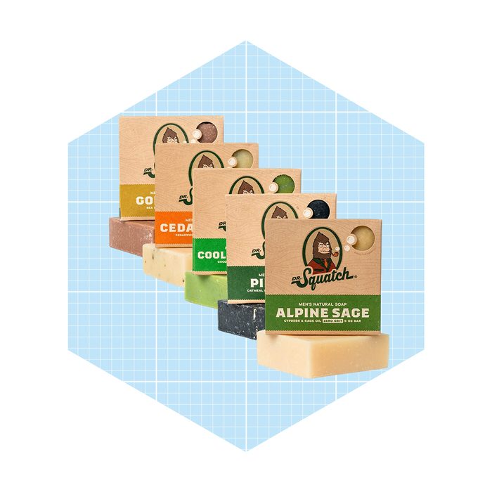 Five distinct bars of soap are arranged with their packaging facing forward, displayed on a light blue grid background, showcasing various scents and designs.