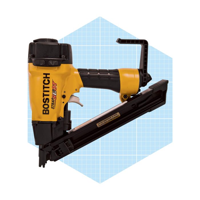 A yellow and black Bostitch nail gun sits against a light blue geometric background, designed for fastening materials together in construction or crafting.
