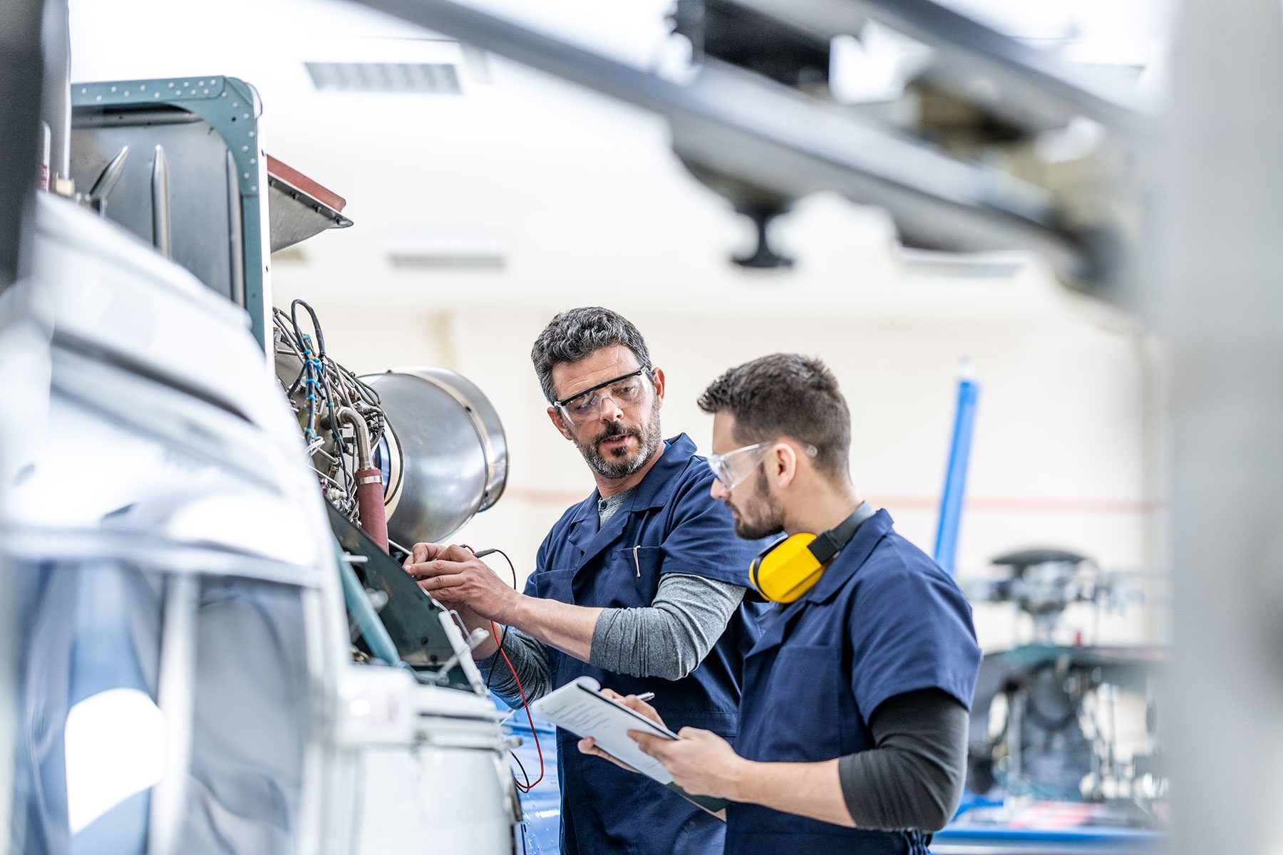 Young aviation mechanics studying to repair engine medium shot