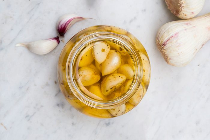 Fresh and pickled garlic cloves on white marble
