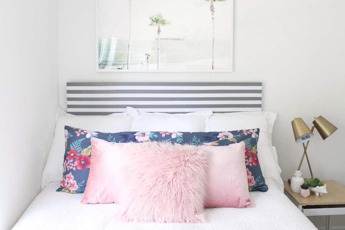 Bed with striped headboard and pink pillowcases